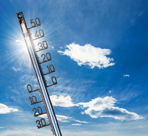 Thermometer, das 30 Grad anzeigt vor strahlend blauem Himmel